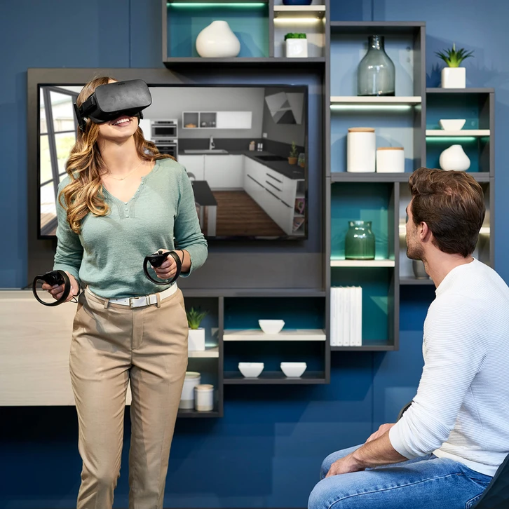 Couple souriant utilisant un ordinateur portable dans une cuisine moderne, consultation collaborative d'écran, atmosphère détendue et professionnelle, interaction digitale à domicile